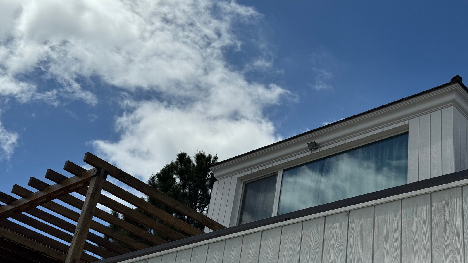 Fachada moderna con pérgola de madera oscura — proyecto CASA CM, por Hermann Arquitectos, en Los Castores